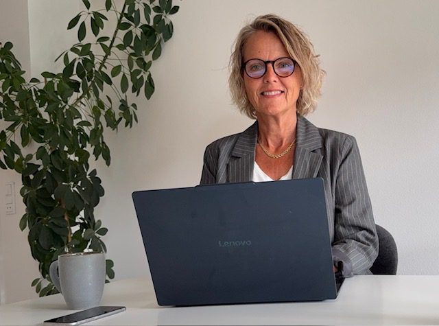 Pernille Nielsen smiler til kameraet ved sit skrivebord